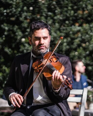Violinista tocando frente a los invitados en un jardín