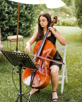 Violonchelista tocando al aire libre bajo una sombrilla